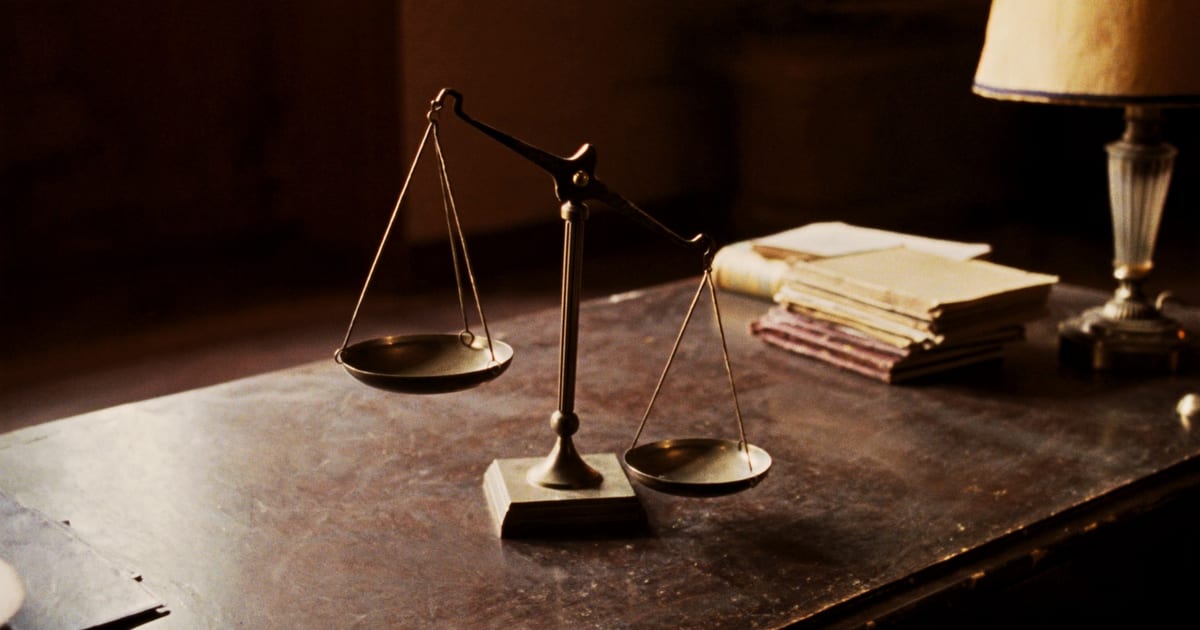 A small brass balance scale on a worn desk beside a stack of old ledgers.