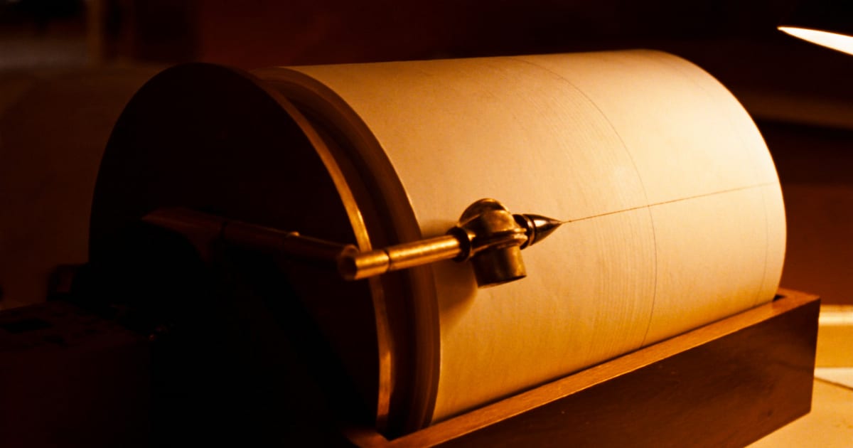 A vintage chart recorder drum, its stylus tracing a continuous line across paper in warm lamplight.